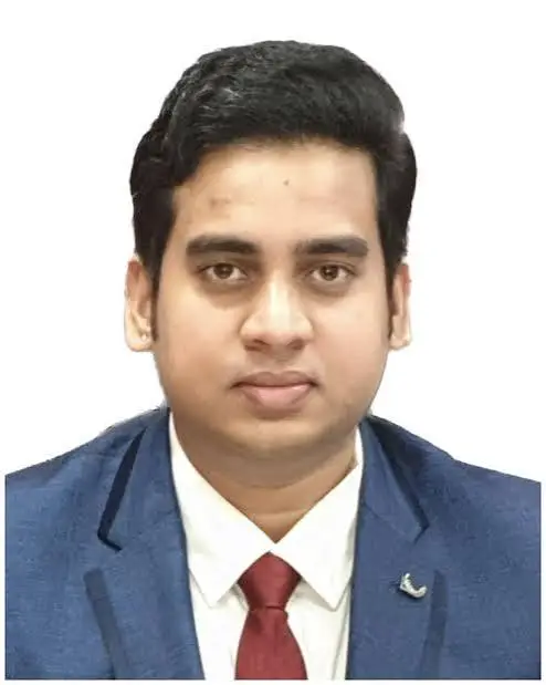 Portrait of a young man in a navy blazer, white shirt, and red tie, against a white background.