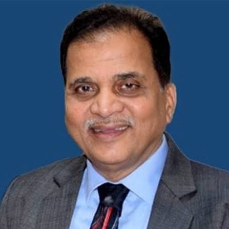 Man in a gray suit and blue shirt smiling against a blue background, head-and-shoulders portrait.