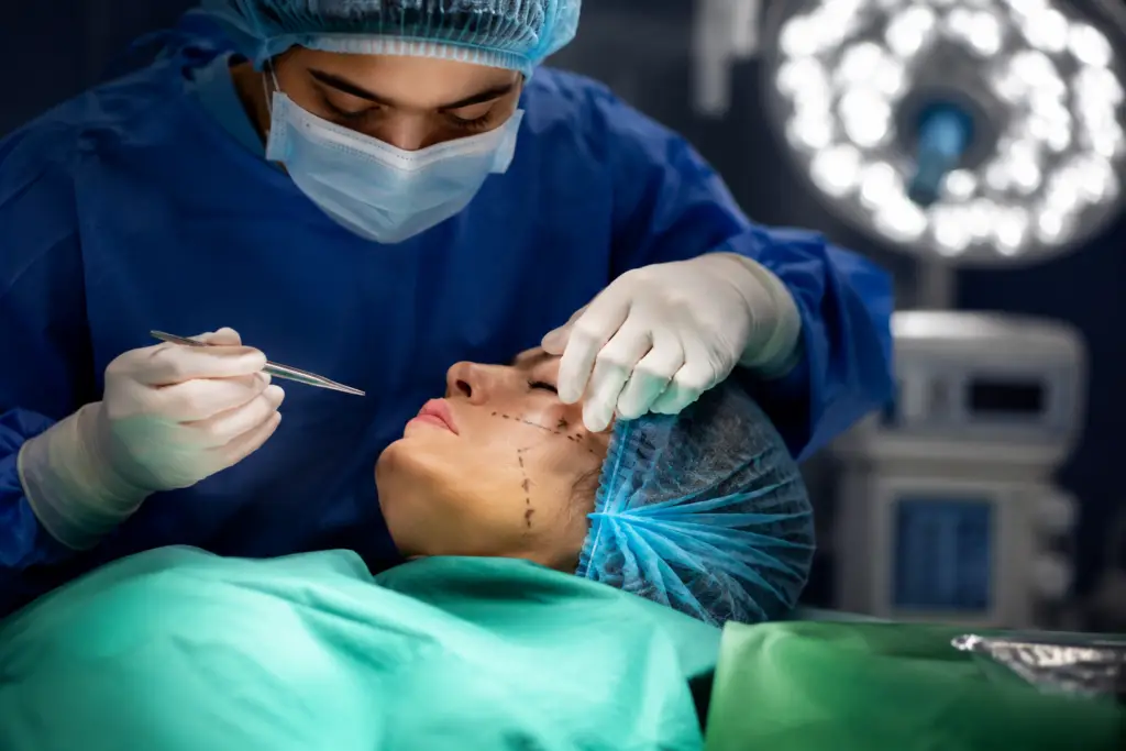 Surgeon in scrubs and mask marking a patient’s face for a cosmetic procedure during surgery.